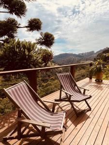 two chairs sitting on a wooden deck with a view at Chalé Roxo na Araucária in Gonçalves