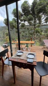 a wooden table with plates and glasses on a deck at Chalé Roxo na Araucária in Gonçalves