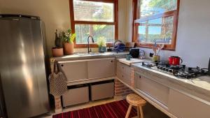 a kitchen with a stainless steel refrigerator and a sink at Chalé Roxo na Araucária in Gonçalves +12 photos