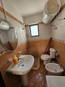 a bathroom with a sink and a toilet and a mirror at Daja's Guest House in Shëngjin