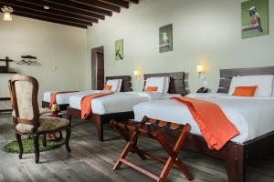 a hotel room with three beds and a chair at Hotel Colonial San Agustin in Quito