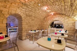 a restaurant with tables and a stone wall at Color Design Hotel in Paris