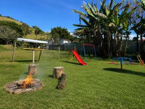 a park with a playground with a fire in the grass at Chalé em Ônibus de 1975 - Ponto Z in São Bento do Sapucaí