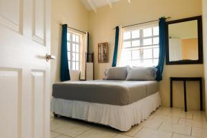 a bedroom with a bed with blue curtains and a window at Cap Estate Ocean View Villa, Gros Islet, St Lucia in Dame de Traversay