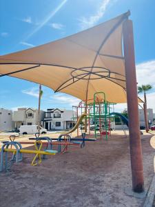 a playground with a yellow umbrella and a slide at Casa en grupo, terraza y alberca compartida in Mexicali