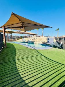 a large umbrella over a pool in a park at Casa en grupo, terraza y alberca compartida in Mexicali