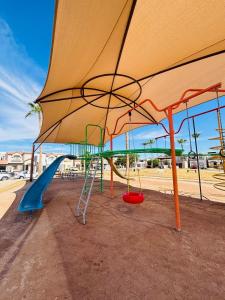 a playground with a slide and a playground umbrella at Casa en grupo, terraza y alberca compartida in Mexicali