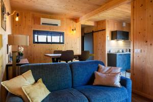a living room with a blue couch and a kitchen at Gîte de la Bridolée, sauna et bain nordique in Lorquin
