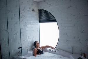 a woman sitting in a bath tub in front of a mirror at Hotel Living 35 Suites by Growing Group in Medellín