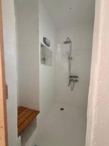 a white bathroom with a shower with a wooden shelf at 7Olives Azure Boutique Apartment in Kastraki +24 photos