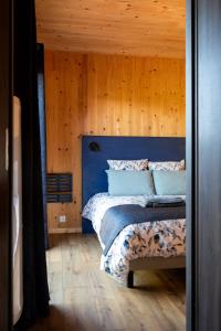 a bedroom with a blue bed with a wooden wall at Gîte de la Bridolée, sauna et bain nordique in Lorquin