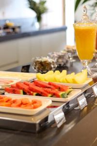 a table with plates of food and a glass of orange juice at Uai Hotel Jaíba in Terra Fôfa