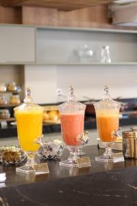three different colored drinks in glass containers on a counter at Uai Hotel Jaíba in Terra Fôfa