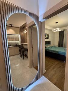 a mirror in a room with a bedroom and a bed at Apartman NOVA in Kragujevac