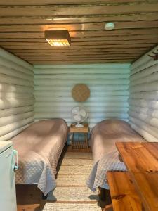 a room with two beds and a table with a fan at Löydön Kartano Camping in Mikkeli