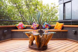 a wooden bench with pillows on a balcony with a table at Hotel Parque España in Mexico City