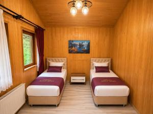 two beds in a room with wood paneling at Auga Apart in Uzungöl