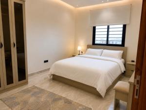 a white bedroom with a large bed and a window at Toot Suites in Abha