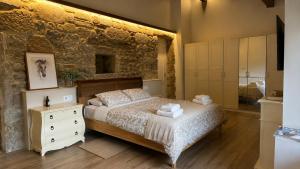 a bedroom with a bed and a stone wall at Finca San Román in Viascón +8 photos