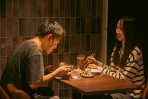 a man and a woman sitting at a table eating food at くらしホテル Hakodate in Hakodate