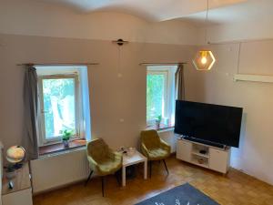 a living room with two chairs and a flat screen tv at Old town Wall Radovljica - Appartment in Radovljica
