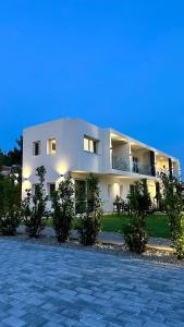 a large white building with trees in front of it at Ammos Maisonettes in Pefkari