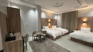 a hotel room with two beds and a table at Qubaa Soul Studio 2-3 in Medina