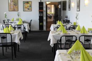 un restaurante con mesas blancas con servilletas amarillas. en Stenbjerg Kro & Badehotel, en Snedsted