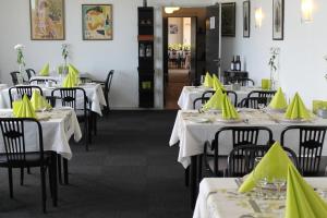 a restaurant with white tables with yellow napkins on them at Stenbjerg Kro & Badehotel in Snedsted