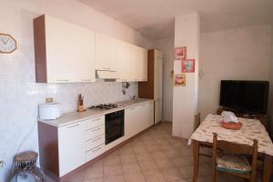 a kitchen with white cabinets and a small table with a table at Fondaco del Capo in Capo Vaticano