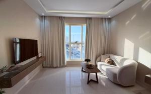 a living room with a white couch and a tv at لينك هوم استديو فندقي دخول ذاتي in Buraydah
