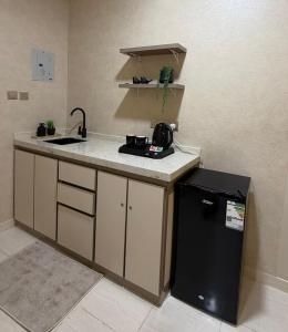 a kitchen with a sink and a refrigerator at لينك هوم استديو فندقي دخول ذاتي in Buraydah