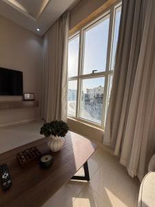 a living room with a table and a large window at لينك هوم استديو فندقي دخول ذاتي in Buraydah