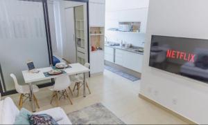 a living room with a television and a table with chairs at Smart Studio Cataratas Luxo in Foz do Iguaçu