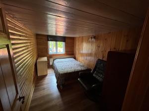 a room with a bed and a chair in a wooden room at Chalet de toutes saisons in Shawinigan
