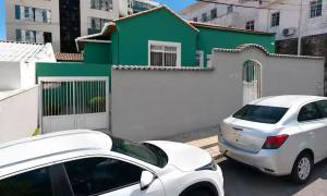 a white car parked in front of a green building at Nônames Urban Hostel in Florianópolis