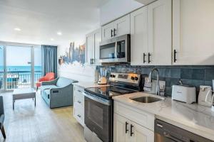 a kitchen with white cabinets and a view of the ocean at Coastal Modern Oceanfront 2BR Yachtsman S506 in Myrtle Beach