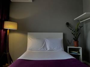 a bedroom with a bed with white sheets and a lamp at Patushe Guesthouse in Shkodër