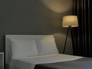 a bed with a white pillow and a lamp at Patushe Guesthouse in Shkodër