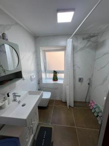 a bathroom with a sink and a toilet and a window at Vila 4 Stinet in Pogradec +26 photos