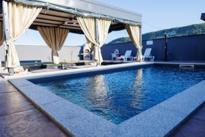 a swimming pool with a pavilion and some chairs at Villa Merak House in Bijelo Brdo