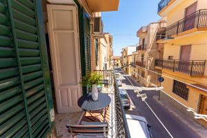 a balcony with a table and chairs on a street at Casa Antonella in Trabia
