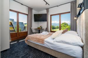 a bedroom with a large bed with a large window at Home Tatra in Biały Dunajec