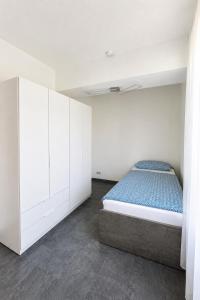 a white bedroom with a bed and white cabinets at Four Rooms Allgäu Apartment in Wangen im Allgäu