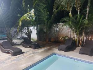 a swimming pool with chairs and palm trees at Paradise 1 in Jacó