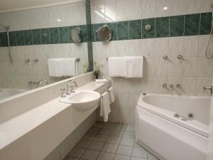 a white bathroom with a tub and a sink and a bath tub at Gateway on Monash in Clayton North +23 photos