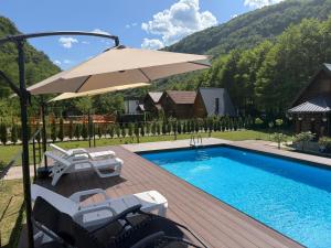 a swimming pool with an umbrella and chairs and a table at Holiday Home UnaPark in Krakovo