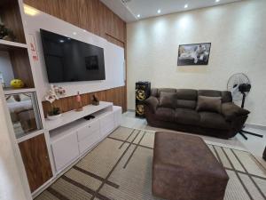 a living room with a couch and a flat screen tv at Casa Rosa in Cuiabá