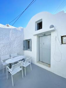 a patio with a table and chairs and a garage at Argonaut House in Anafi