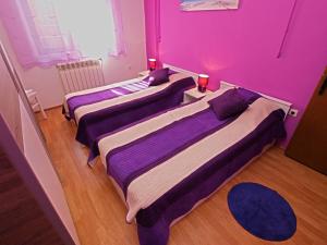 2 Betten in einem Zimmer mit lila Wänden und Holzböden in der Unterkunft Apartments Orange 768 in Fažana